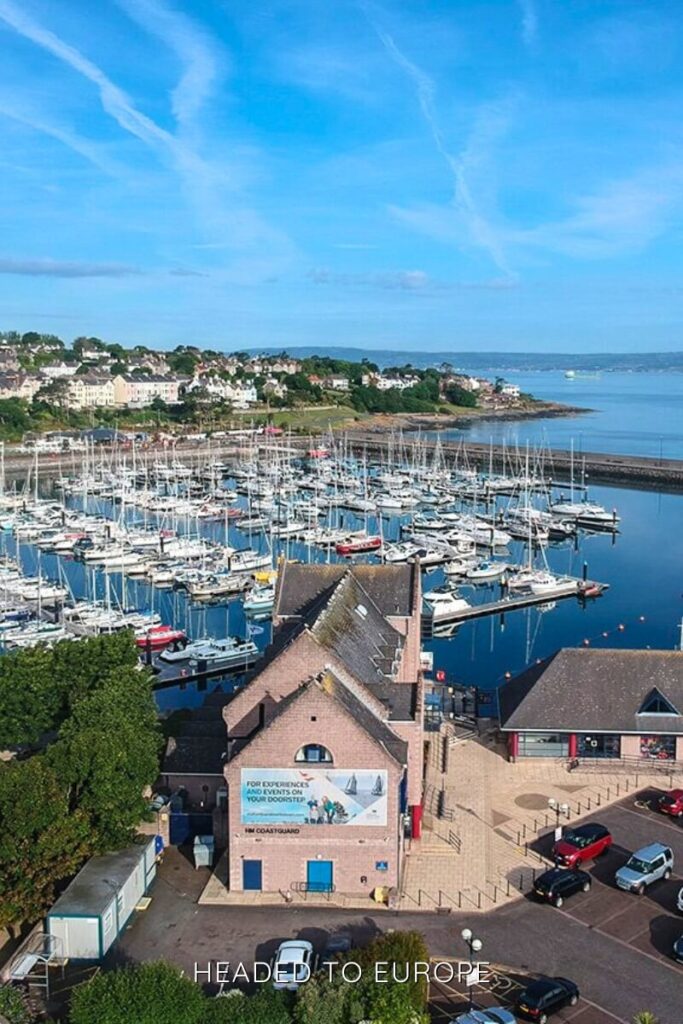 Aerial view of the Bangor Marina, filled with rows of sailboats and surrounded by a charming coastal town under a bright blue sky.
