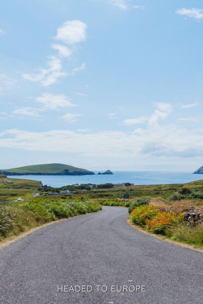 A winding country road in Galway leading to the Atlantic coastline with distant green headlands, perfect for scenic Weekend Breaks in Ireland.