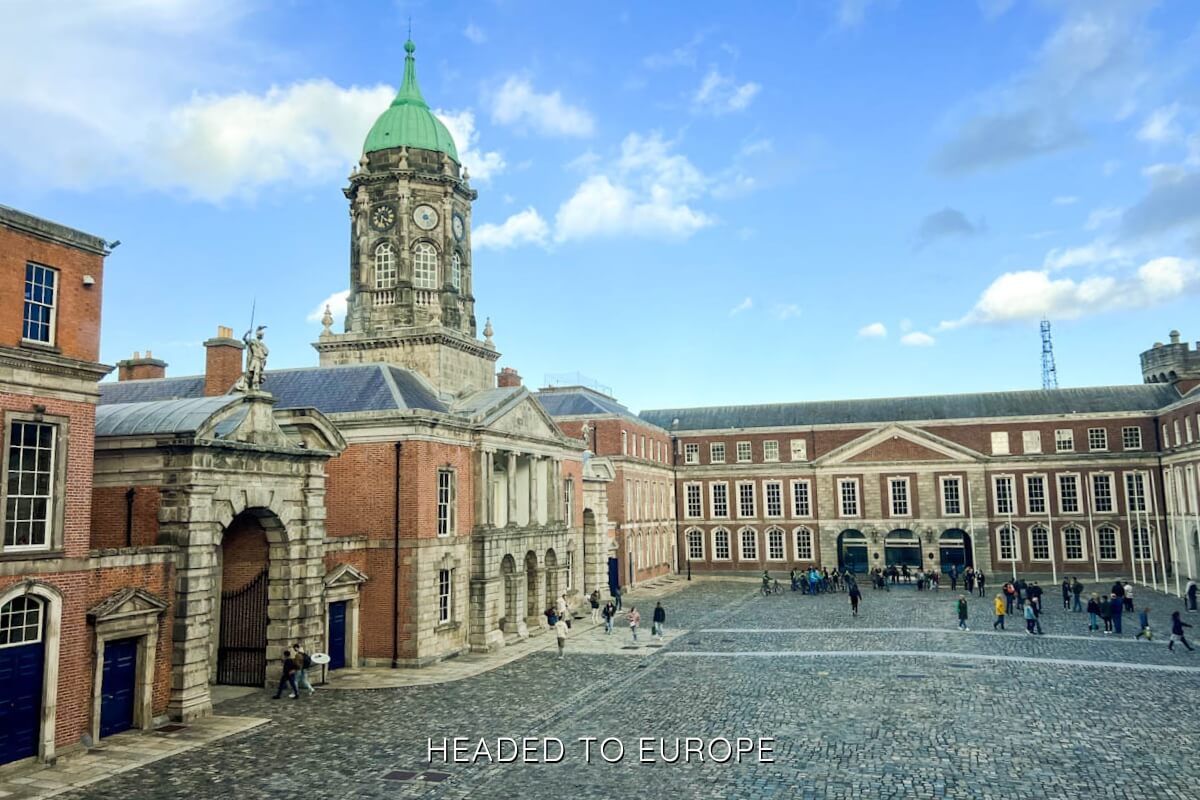 Dublin Castle courtyard under a bright blue sky, with its Georgian clock tower and red-brick buildings surrounding the cobblestone square, capturing one of the most Instagrammable places in Dublin for history and architecture lovers.