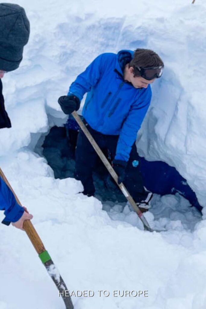 A group of guides in blue winter jackets dig into the snow as part of a safety or navigation activity on the Into the Glacier tour. The deep snow and coordinated effort reflect the rugged nature of exploring Iceland's glacial environment.