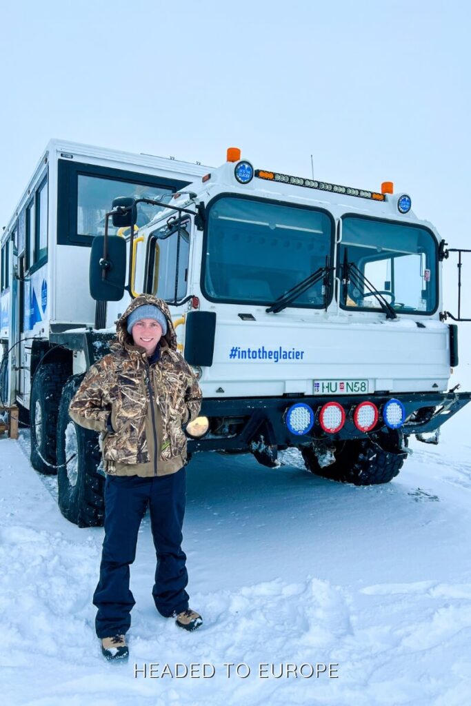 Tucker poses in front of the large glacier truck used on the Into the Glacier tour in Iceland. The massive snow vehicle, labeled with the tour’s hashtag and logo, is built to navigate the snowy terrain en route to the glacier tunnel.