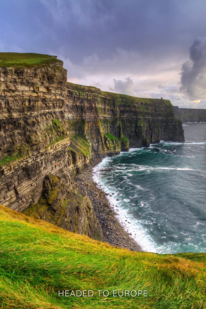 Towering cliffs plunge into the Atlantic Ocean at the Cliffs of Moher under dramatic skies, a top natural attraction for Weekend Breaks in Ireland.