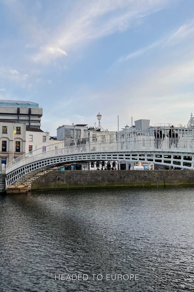 The iconic white Ha’penny Bridge curves over the River Liffey beneath a pastel sky, making it a must-see and Instagrammable place in Dublin for cityscape lovers.