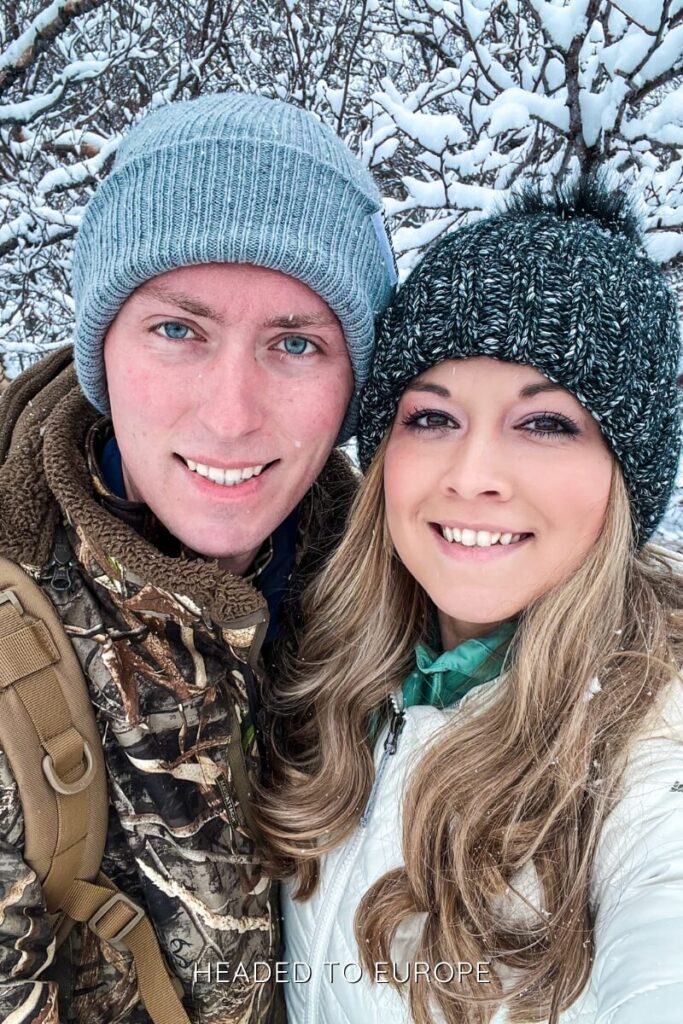 Tucker and Janae take a selfie surrounded by snow-covered trees, bundled warmly for the Icelandic winter.
